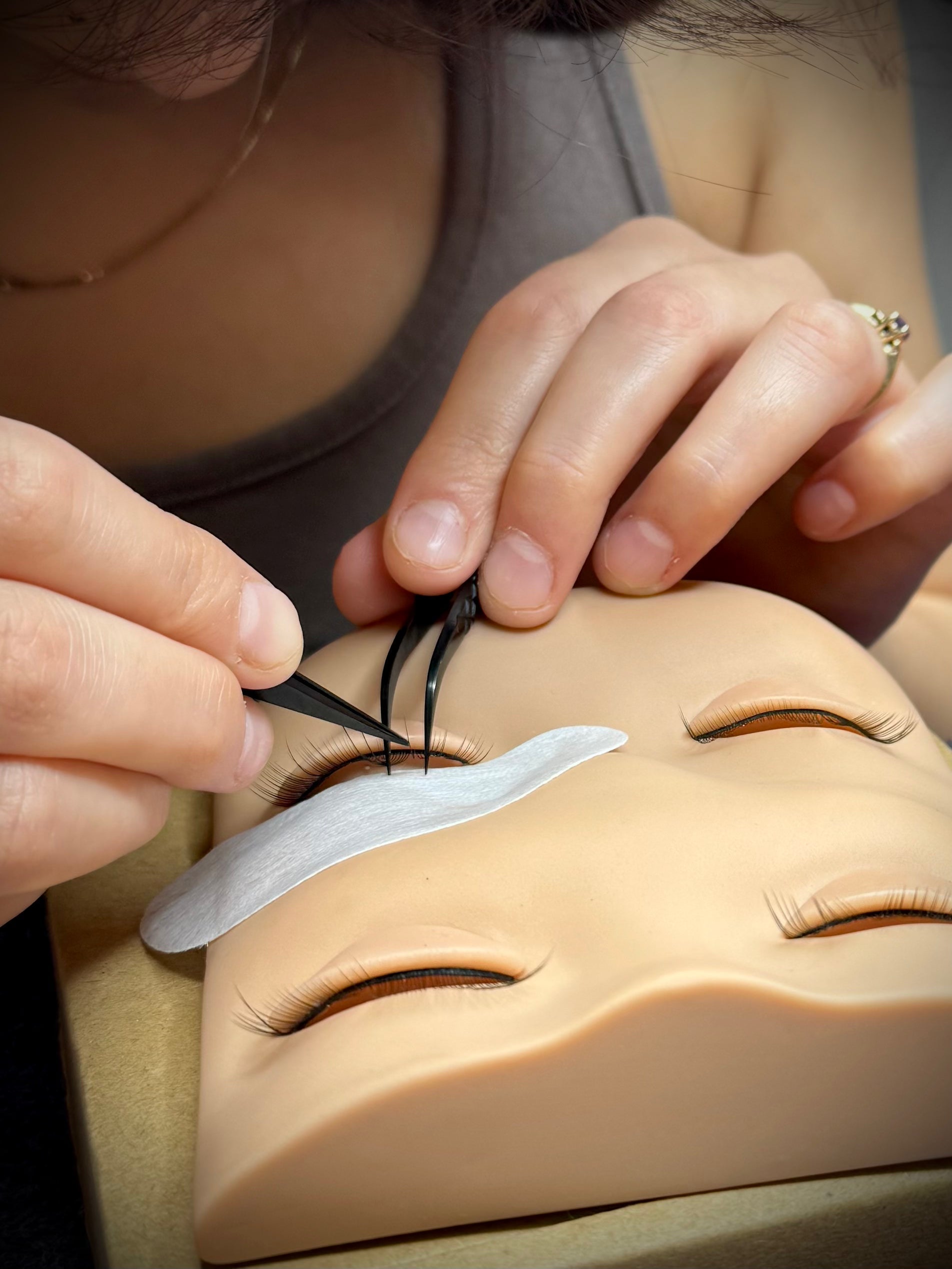Beginner lash artist practicing isolation with tweezers during lash extension training